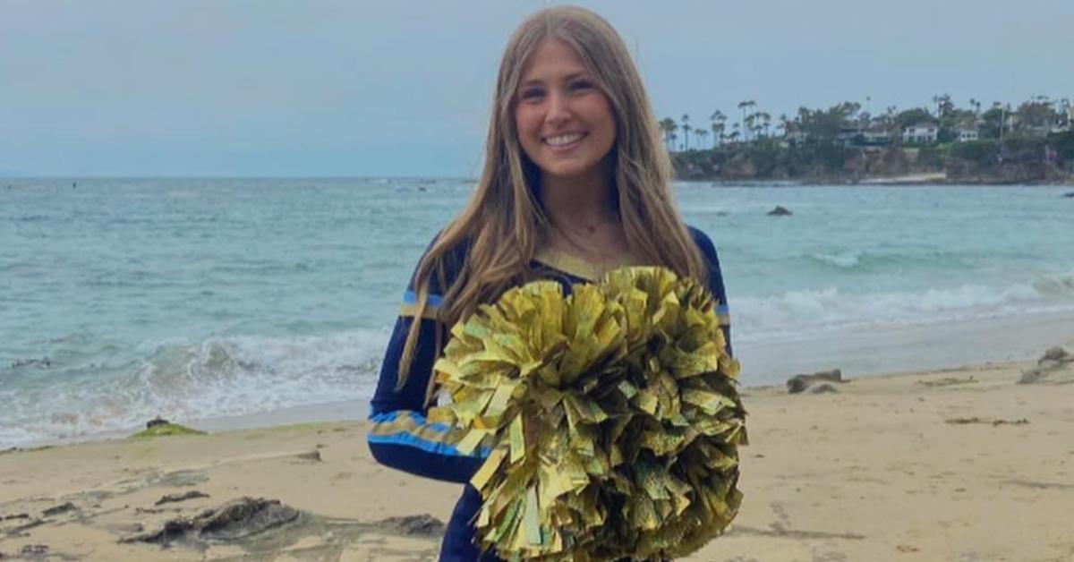 Emily Gold poses for a picture on the beach, wearing her cheerleading uniform