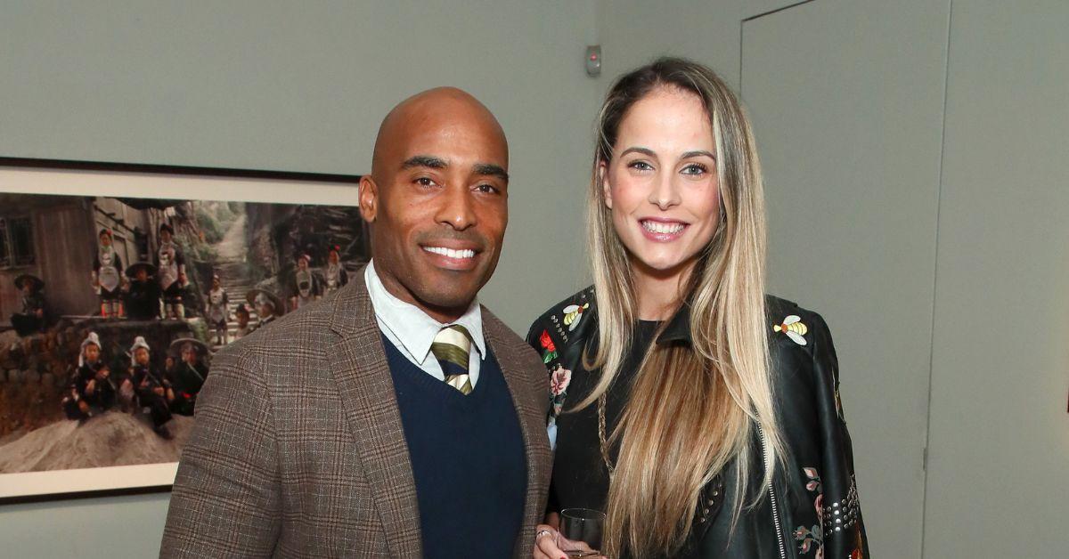 Tiki Barber and Traci Johnson pose for a photo in front of a painting at an event