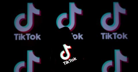 A TikTok logo on a phone with logos behind it.