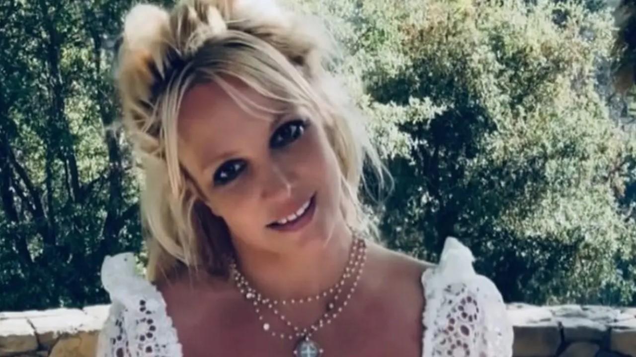 Britney Spears smiling outside in a lace shirt