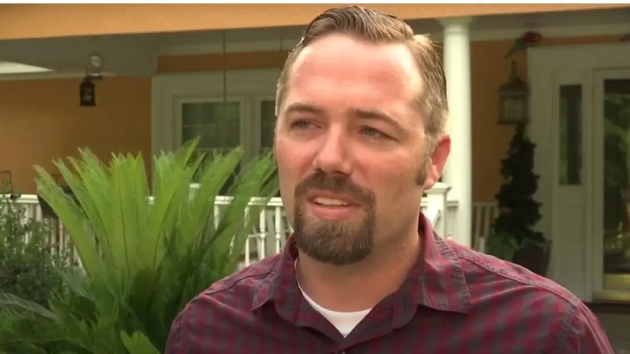 Sidney Moorer standing outside a house in a maroon shirt