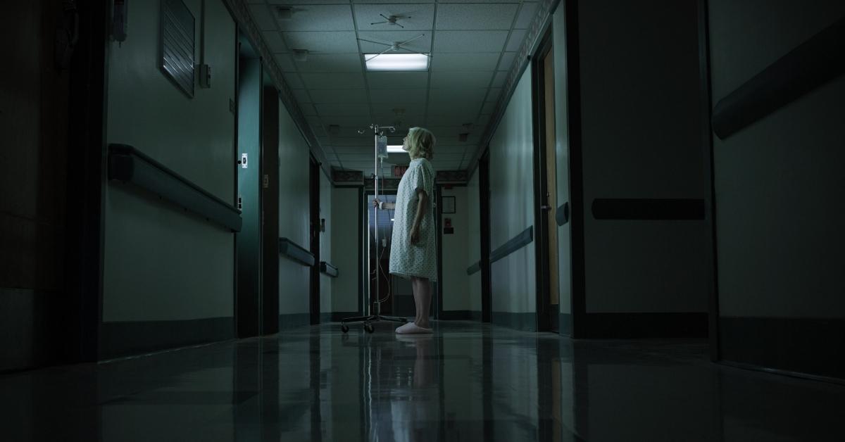 girl with iv drip in dark hospital hallway