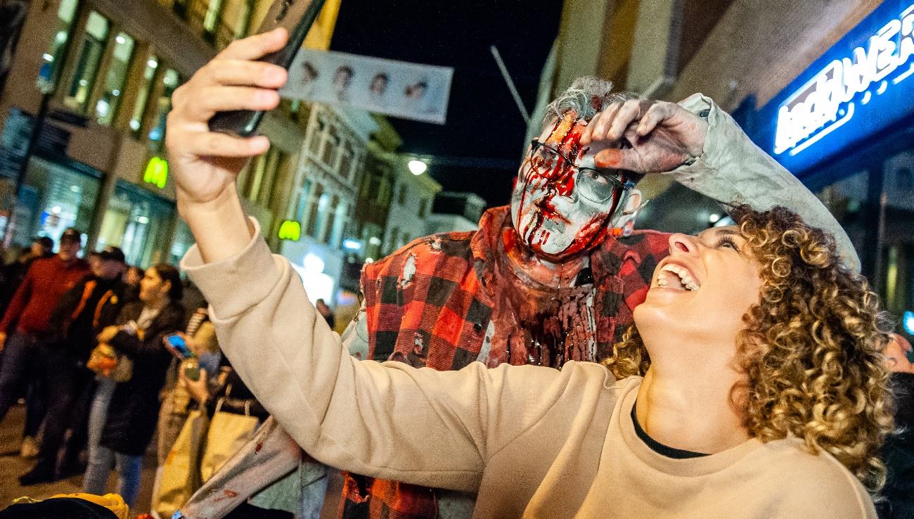 A woman is taking a selfie with one of the zombies, during the Zombie walk organized in the center of Arnhem