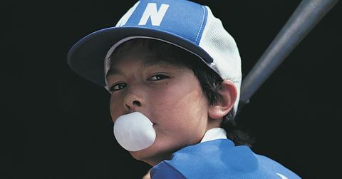 A boy blowing bubbles at bat in blue.