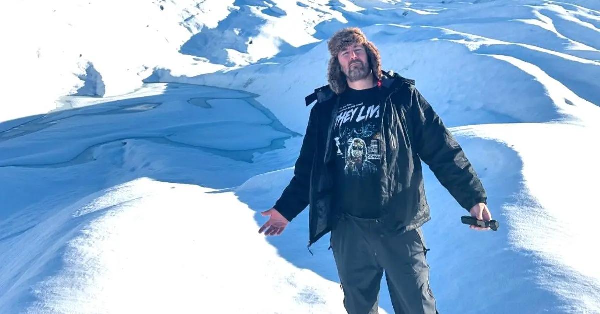 Adam the Woo stands near a snowy hill while traveling across the U.S.