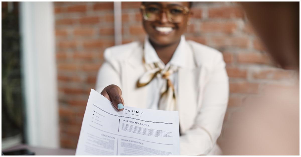 A Black woman showing her resume at an interview