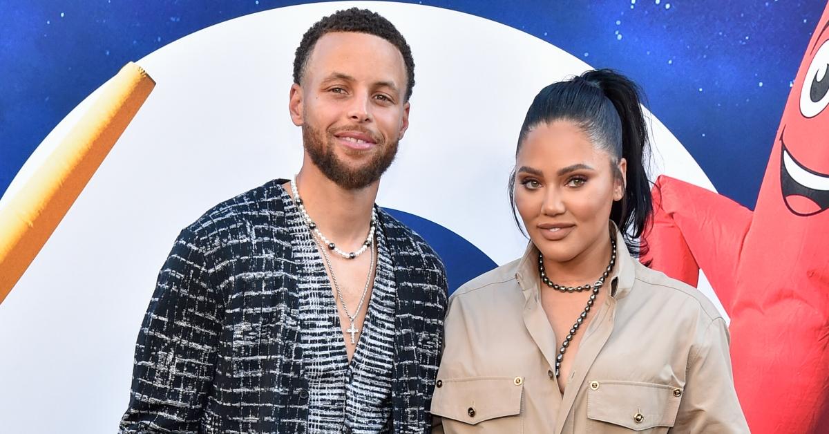 Steph Curry wears grey and white cardigan and smiles next to Ayesha Curry.
