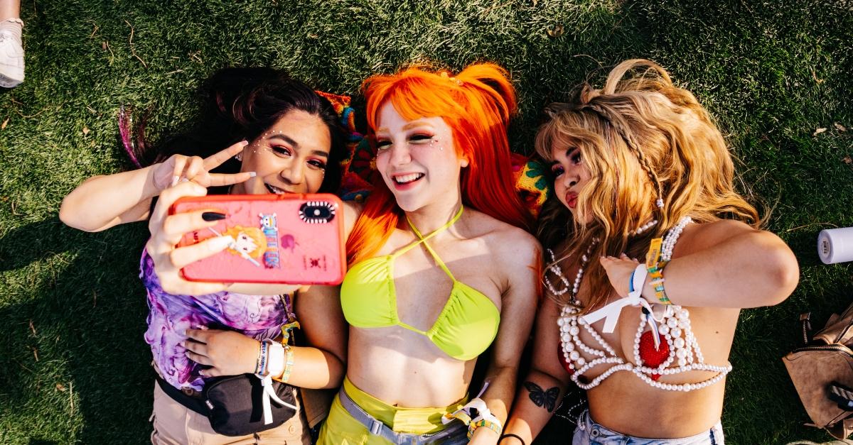 Three Coachella 2023 concert-goers pose for a selfie in the grass.