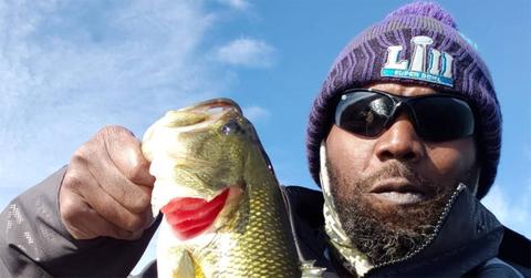 Randy Moss in a knit hat holding a fish.