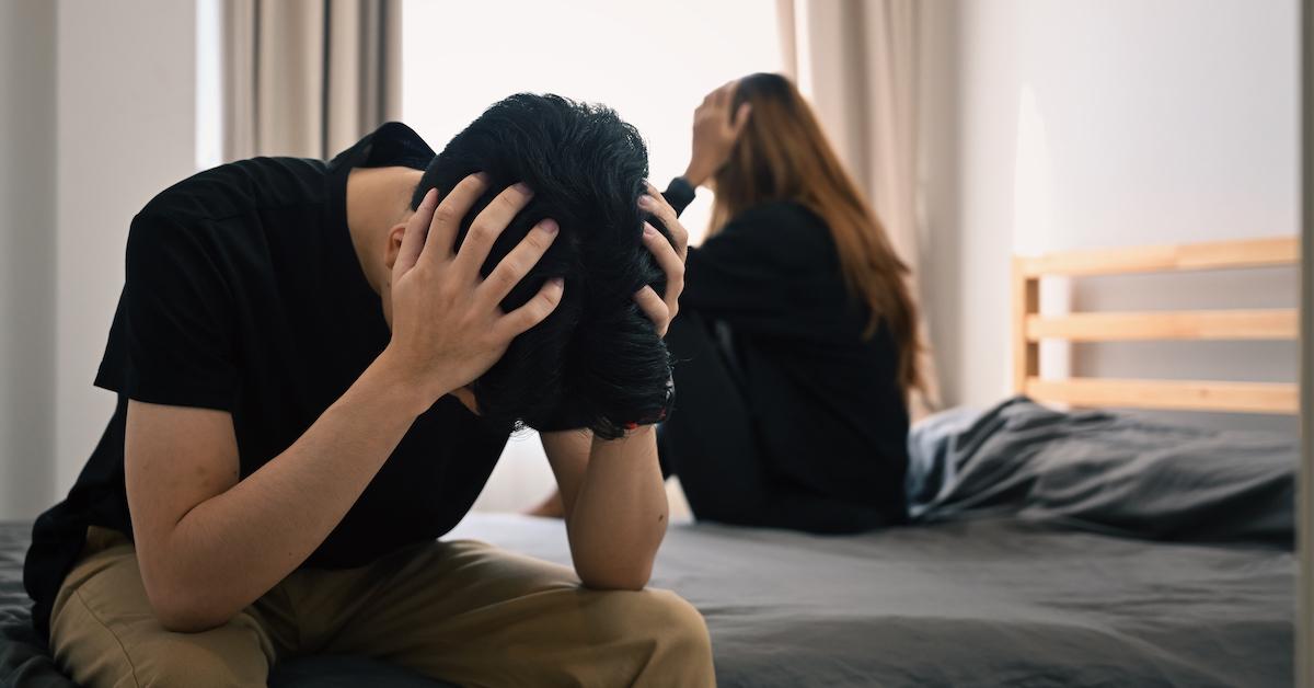 A couple arguing and sitting on a bed