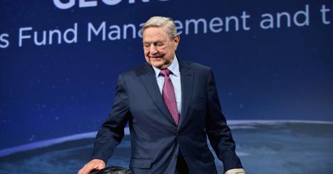 George Soros on stage in a suit.