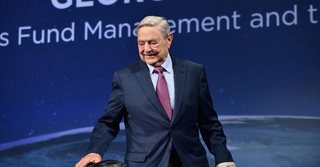 George Soros on stage in a suit.