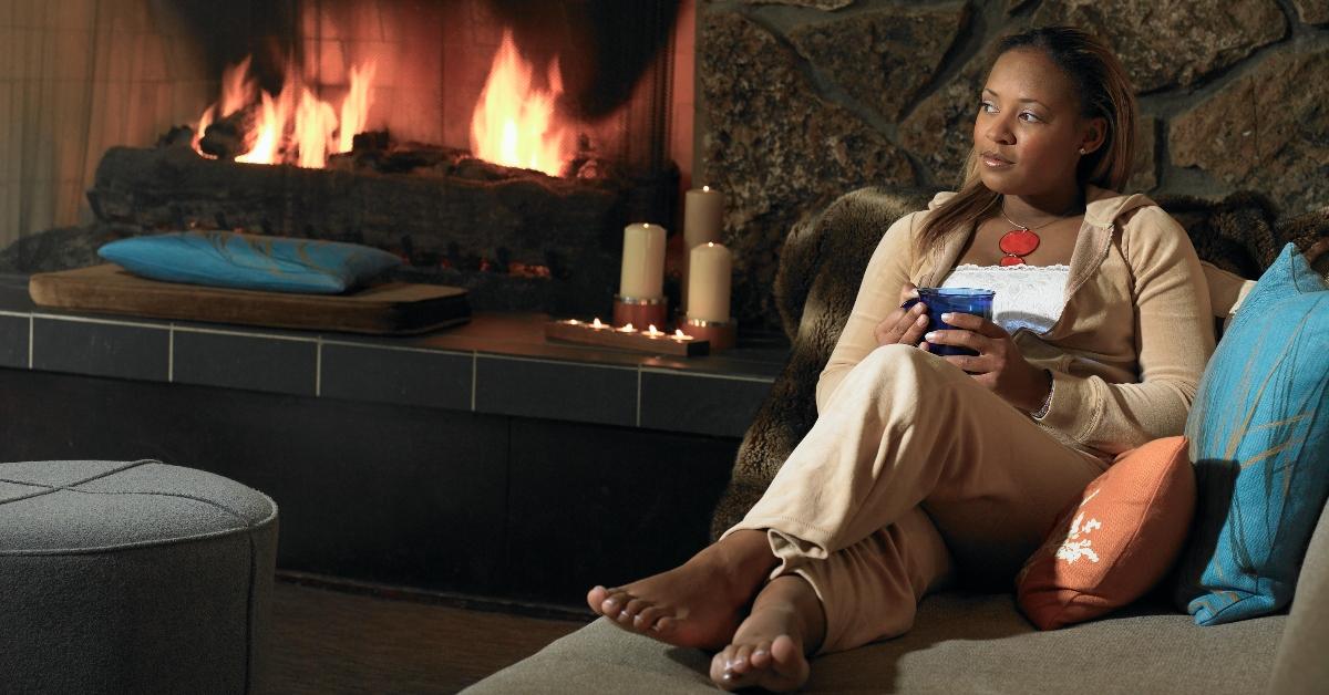 A woman sits in front of a roaring fire