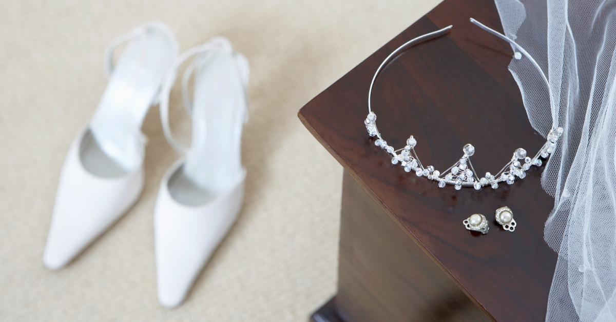 wedding tiara and earrings on cabinet, white shoes on floor 