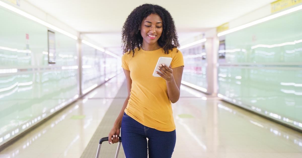 A woman on the phone carrying a suitcase