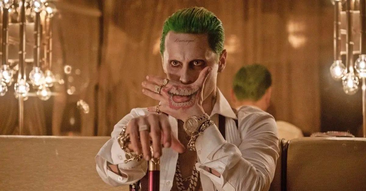 Jared Leto as the Joker covering his mouth with a tattooed hand.