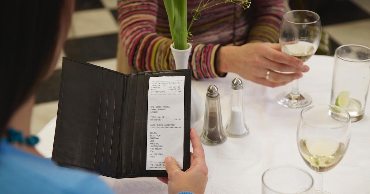 A person holding a bill at dinner