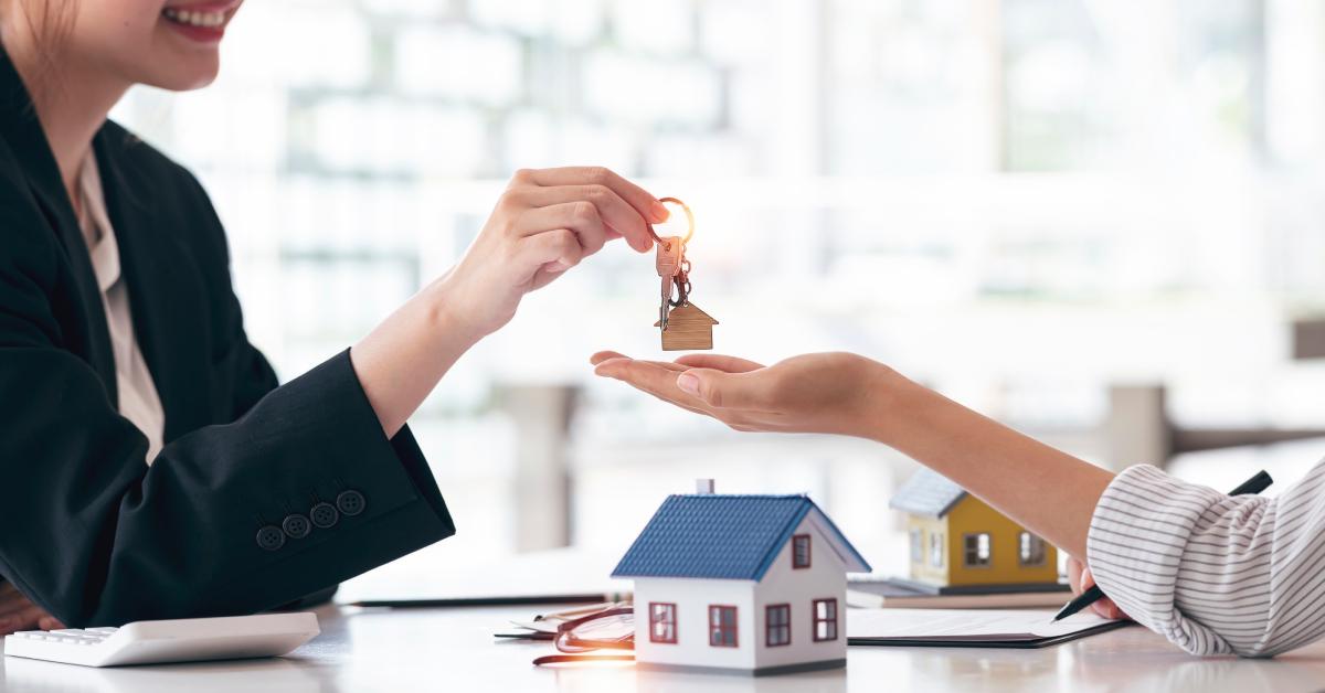 A real estate agent gives house keys to their client.