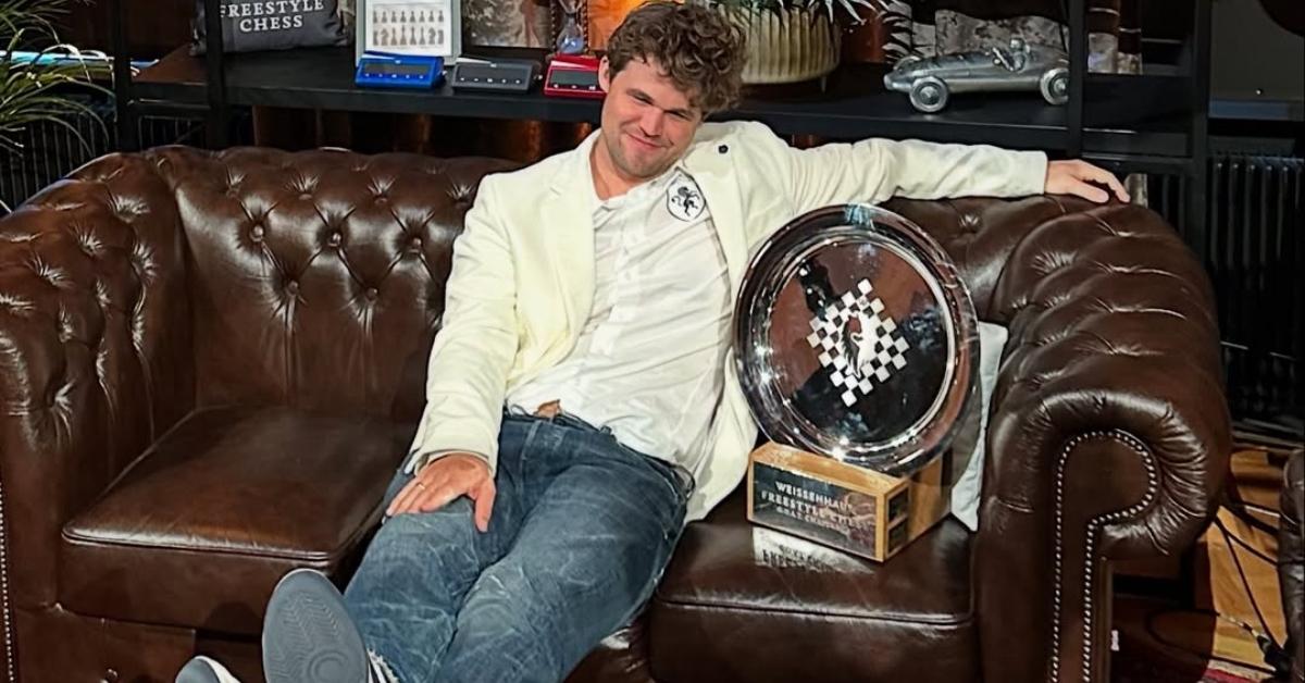 Magnus Carlsen sits on a couch with a trophy