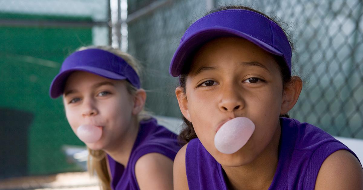 Two girls blowing bubbles in the dugout. 