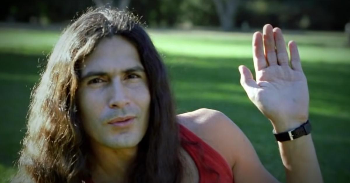 Rodney Alcala holds his hand up in a photograph