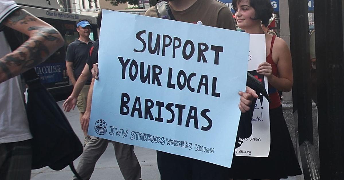 A person holding a sign to support baristas during a protest outside of a Starbucks