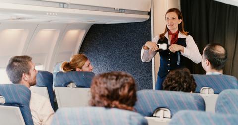 A female flight attendant demonstrates safety procedures for passengers.