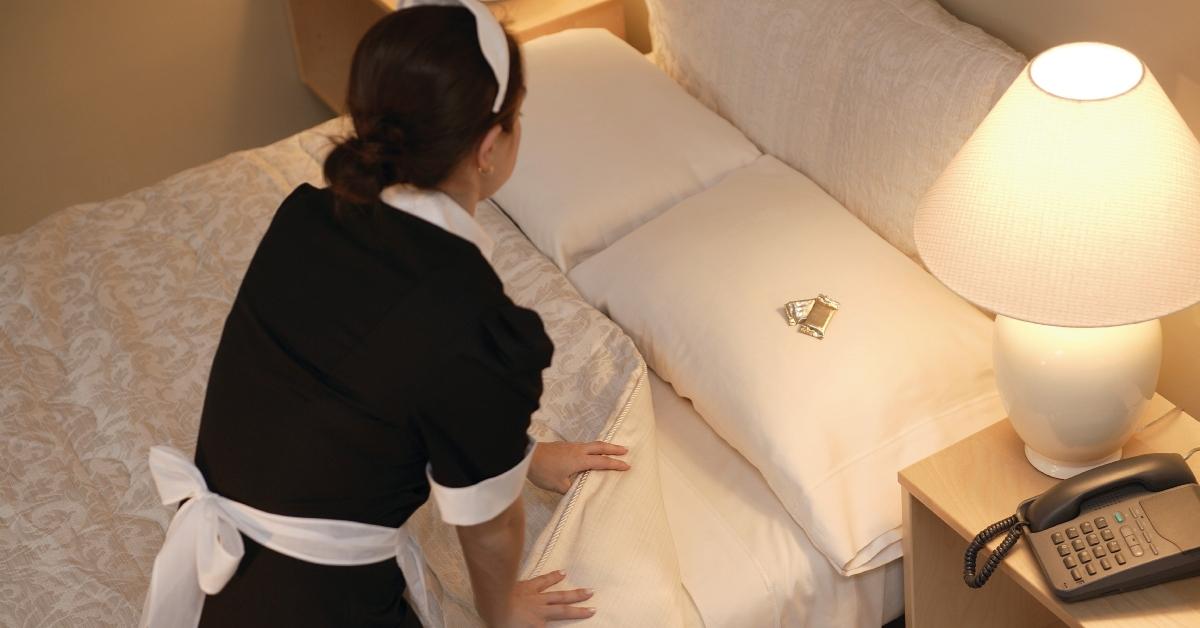 maid making bed and leaving chocolates on the pillow