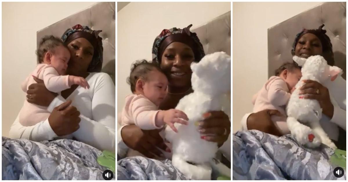 Woman wears a bonnet and sits in bed while she holds her baby niece, who won't stop crying until she gets teddy bear with her mom's heartbeat.