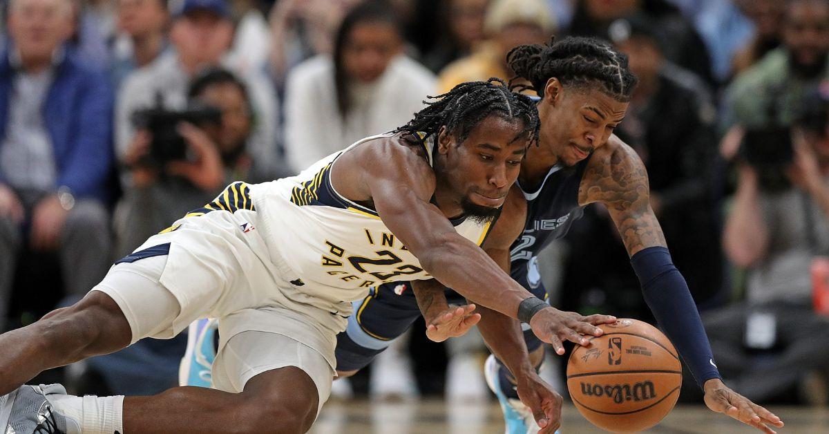 Aaron Nesmith #23 of the Indiana Pacers and Ja Morant #12 of the Memphis Grizzlies fight for the ball