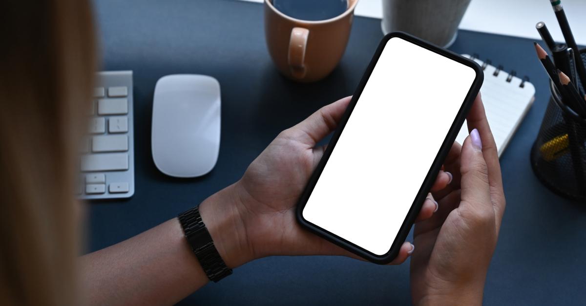 A young woman's iPhone displays a white screen.