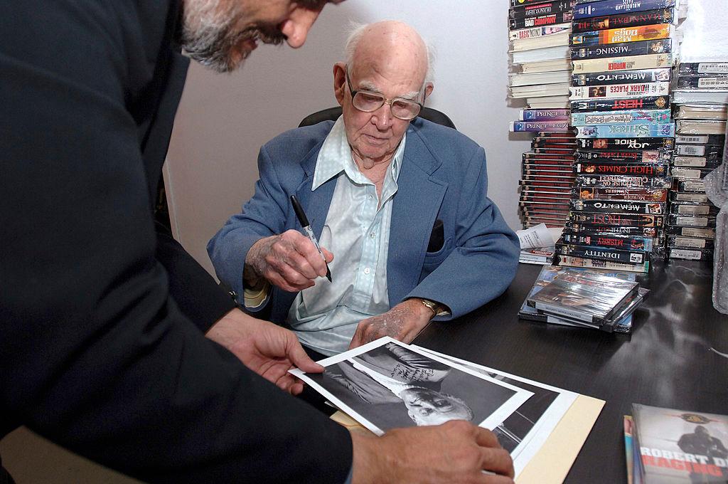 Dabbs Greer signing a photograph with his autograph