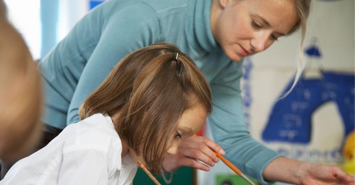 teacher helping student paint