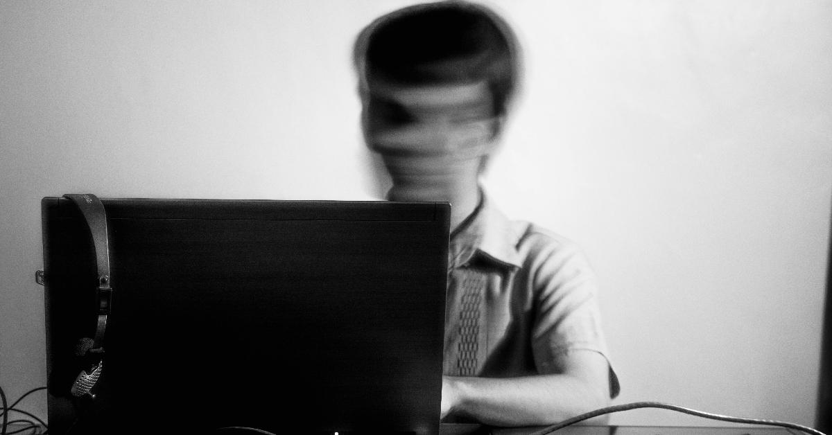 Blurry black and white photo of a teenager on a laptop