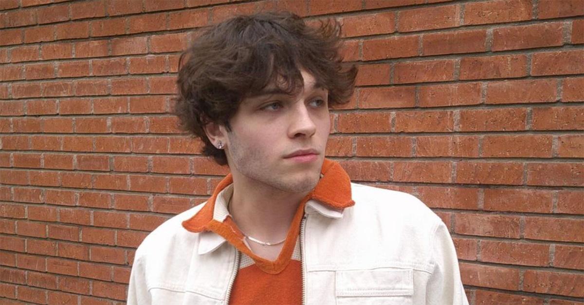 Matthew Sturniolo wearing a jacket standing against a brick wall.