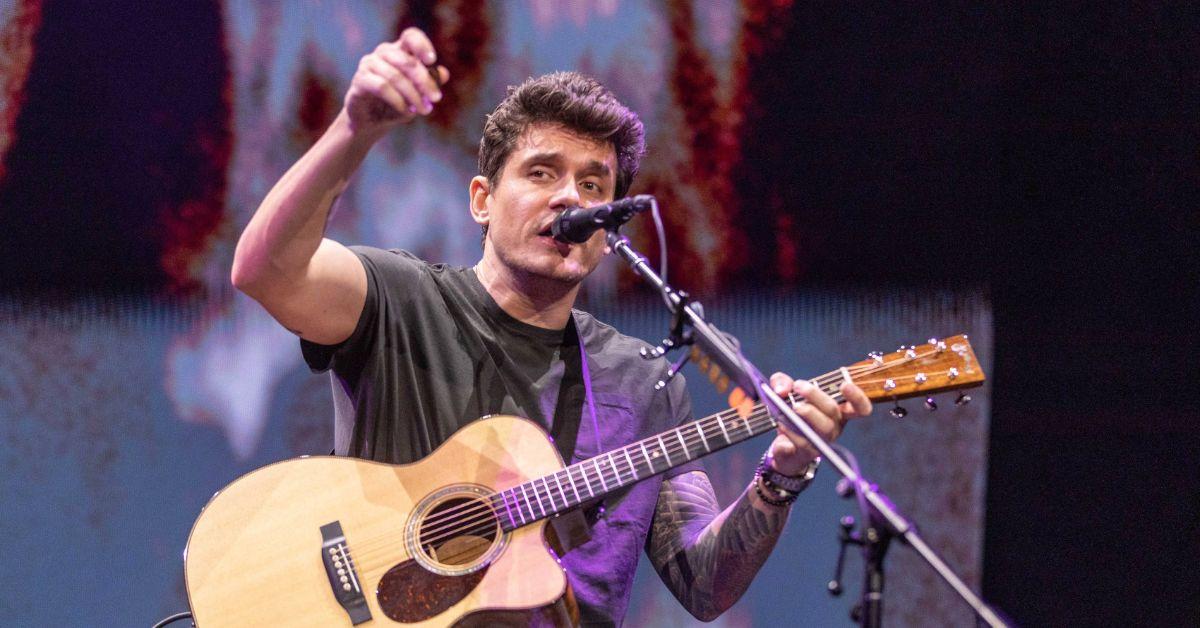 John Mayer performing acoustic guitar on stage. 