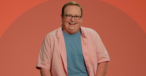 Brandon from The Circle smiles in front of an orange background