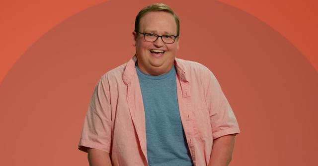 Brandon from The Circle smiles in front of an orange background