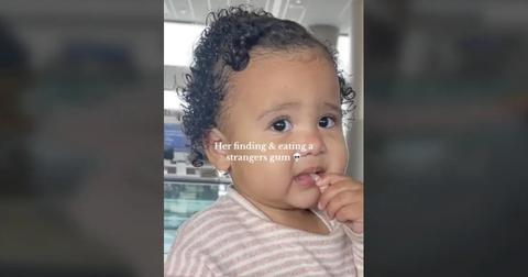 The baby putting the gum in her mouth at the airport