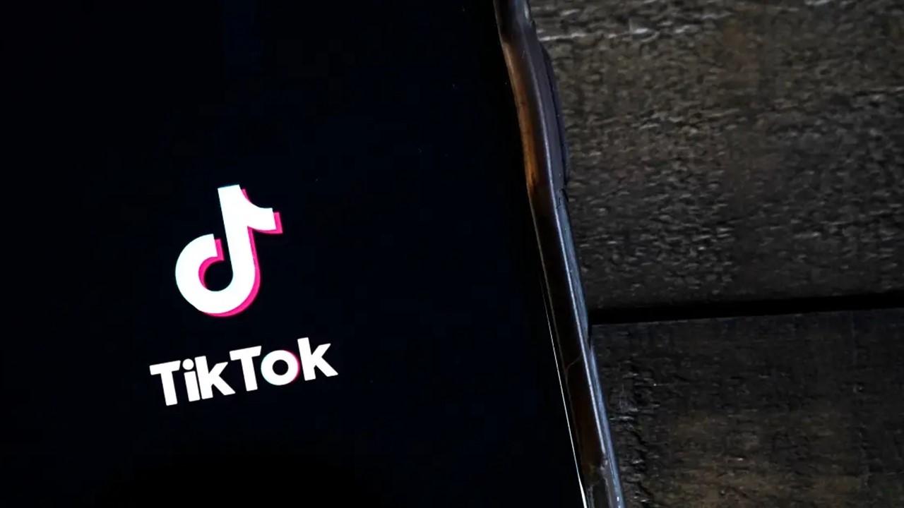 A cell phone with the TikTok logo sitting on a wooden table.