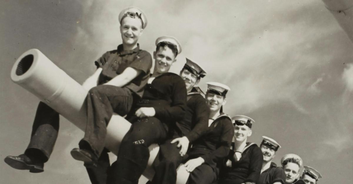 Sailors seated on a gun barrel
