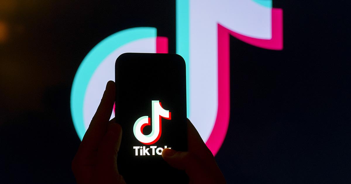 A TikTok logo on a phone with the TikTok logo behind it. 