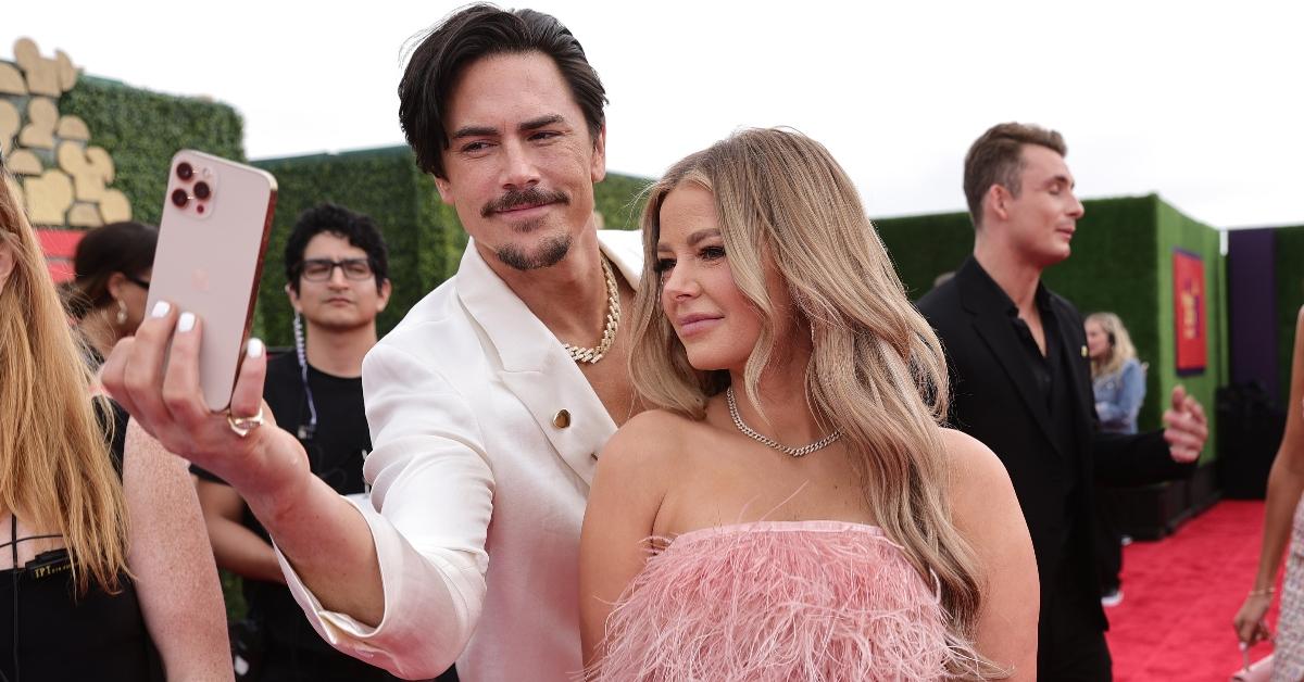 Tom Sandoval in white jacket with white nail polish, Ariana Madix in pink dress, taking selfie on red carpet