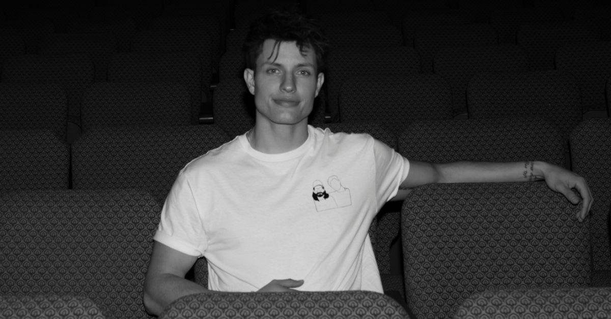 Matt Rife sitting in an auditorium chair.