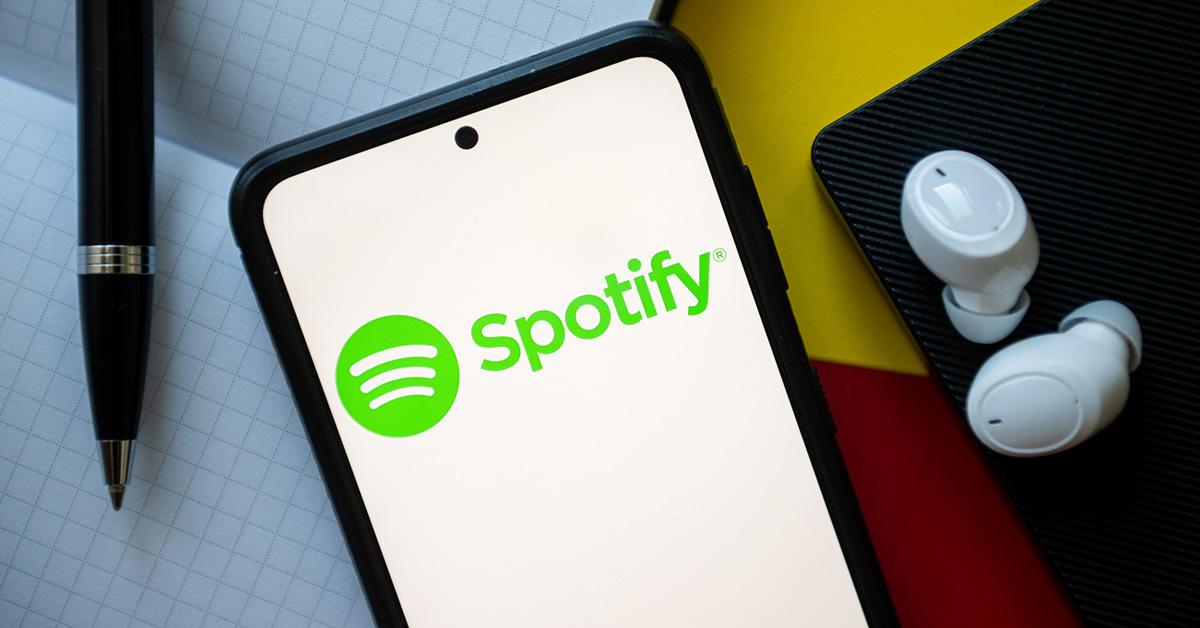 Spotify logo on a phone with earbuds next to it. 