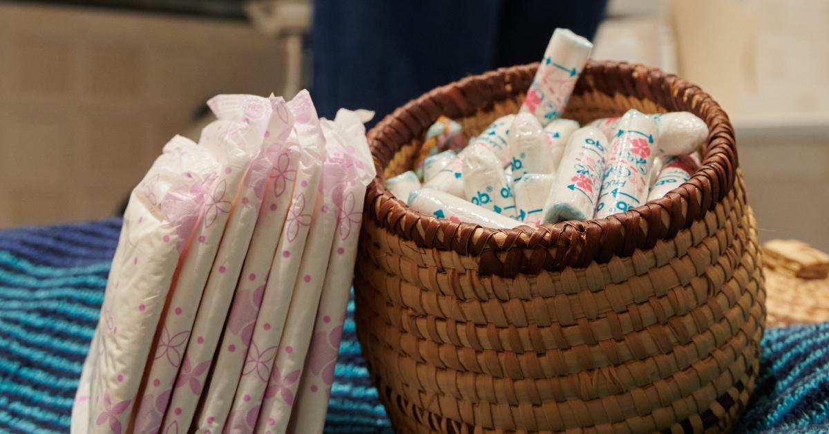 Pads and tampons sitting on a counter in a public bathroom.