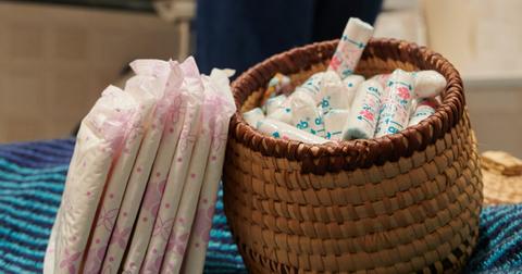 Pads and tampons sitting on a counter in a public bathroom.