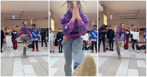 Guy in purple Bape jacket and jeans gets sturdy in the mall with a crowd watching and recording.