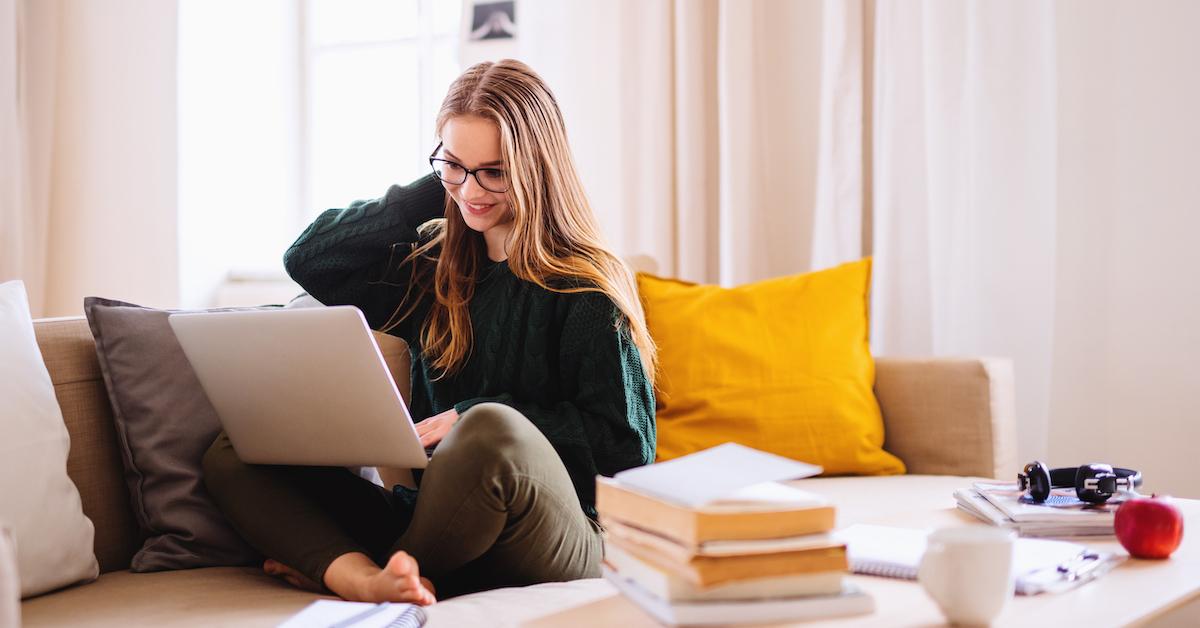 Student sitting on sofa and happily receiving her ACT scores online