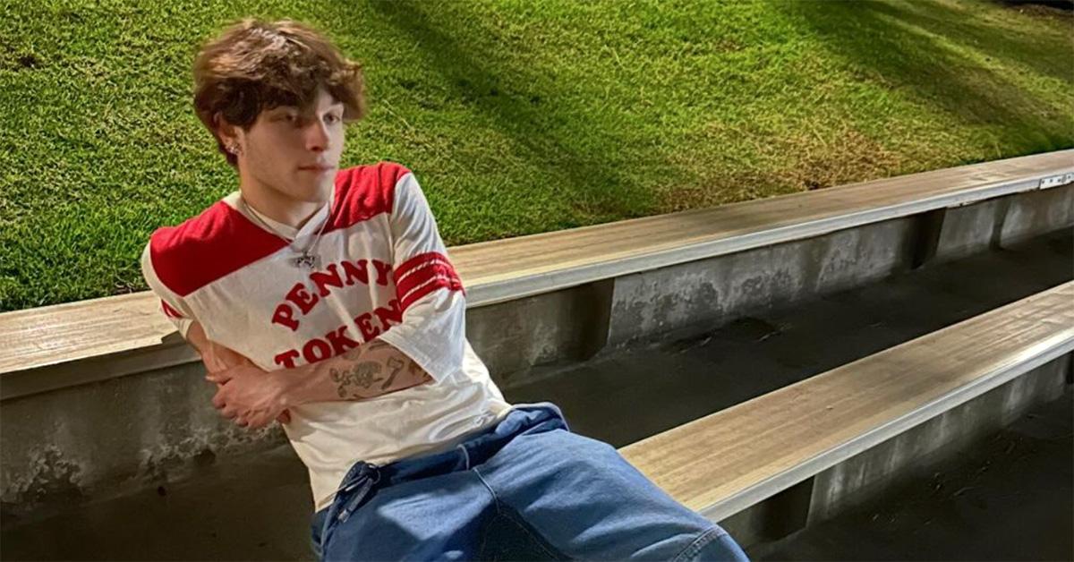 Matthew Sturniolo sitting on some outdoor bleachers in jeans and a t-shirt. 